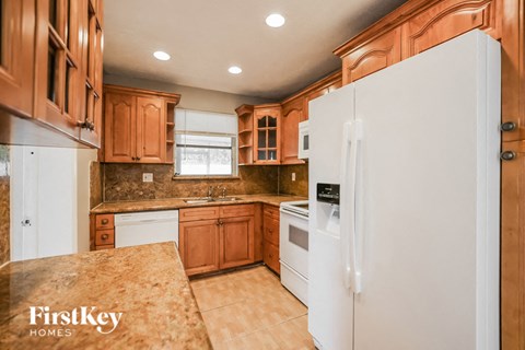 an updated kitchen with white appliances and wooden cabinets
