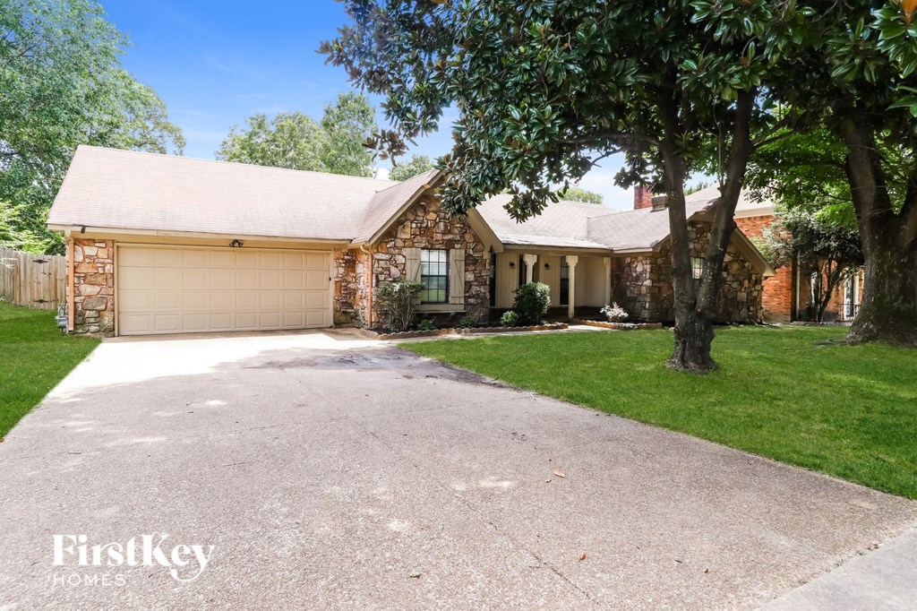 a brick house with a driveway and a tree