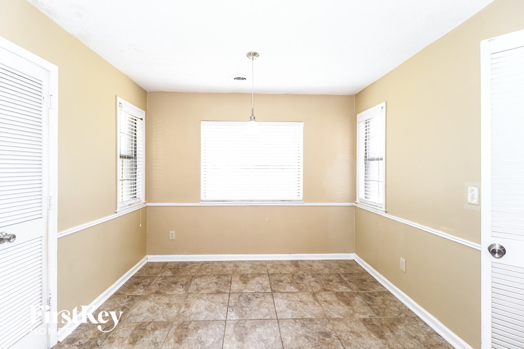 an empty living room with a large window and tiled floors