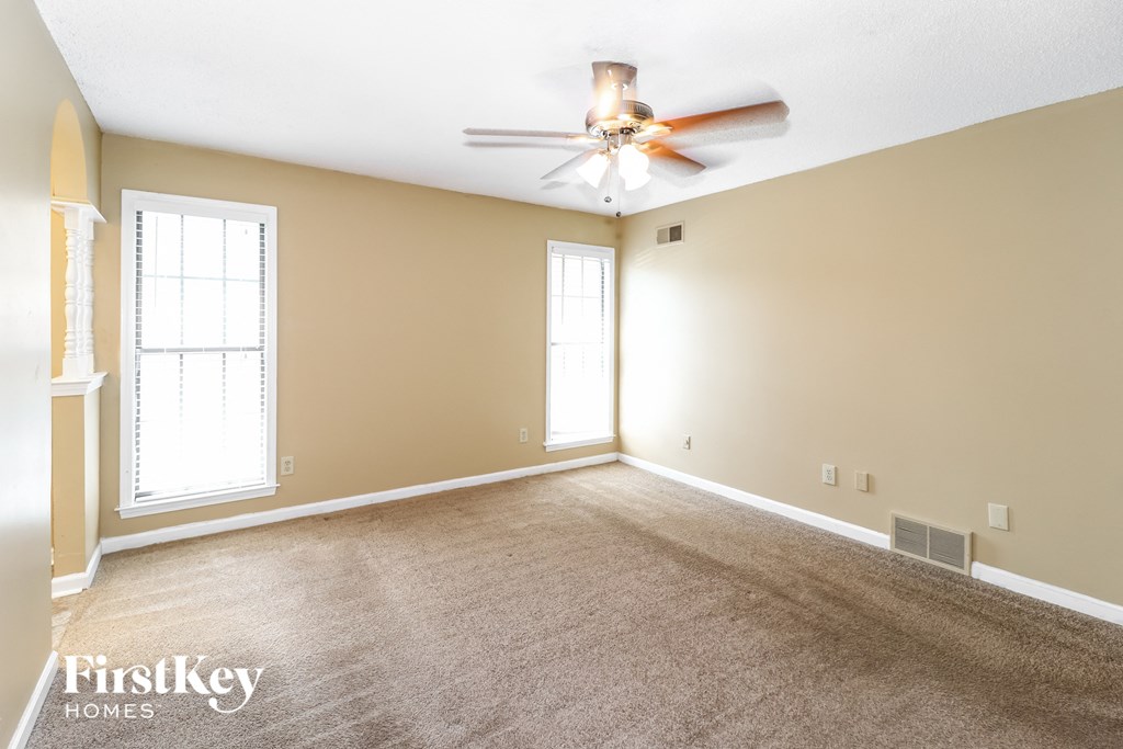 a living room with carpet and a ceiling fan