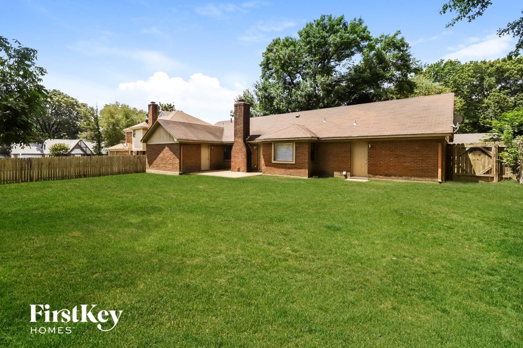 a house with a yard and a fence and a grassy yard