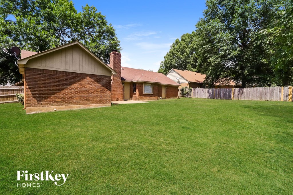 a backyard with a brick house and a green lawn