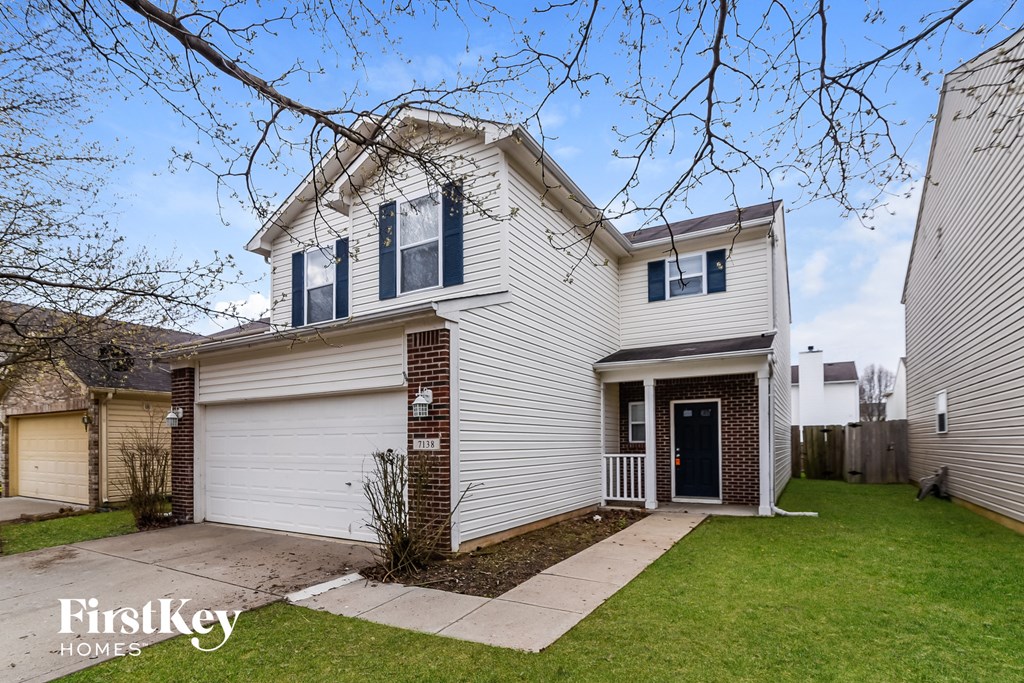 the front of a white house with a yard and a sidewalk