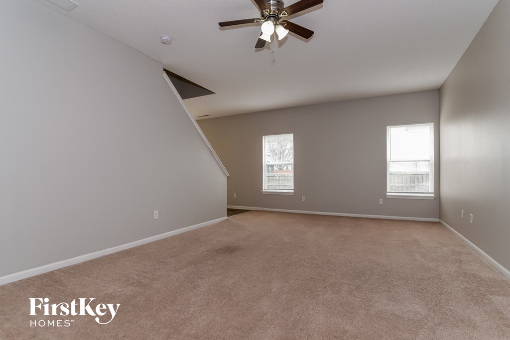 the spacious living room with ceiling fan and carpeting