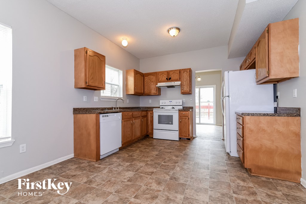 the kitchen is clean and ready to use with wood cabinets and white appliances