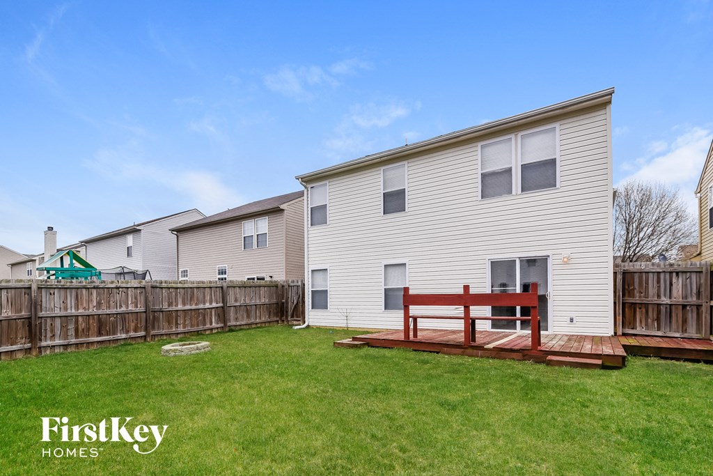 a backyard with a wooden deck and a bench in front of a house
