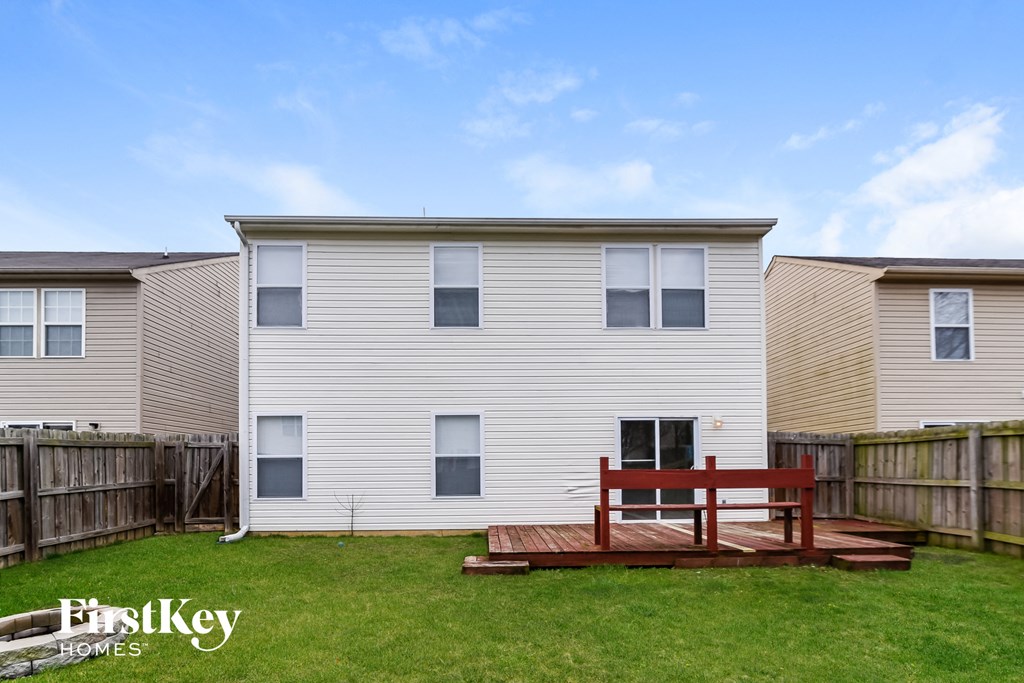 a backyard deck with a red bench in front of a white house