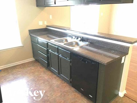 A kitchen with black cabinets and a granite countertop.