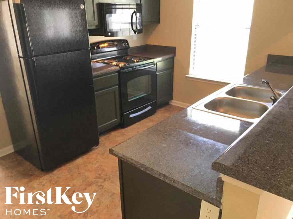A kitchen with a black fridge, black stove, and black oven.