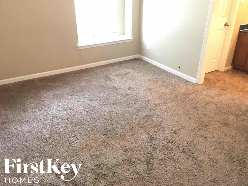 A carpeted room with a FirstKey Homes logo.