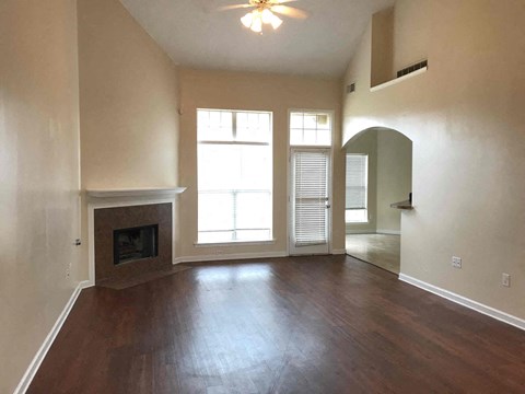an empty living room with a fireplace and wooden floors
