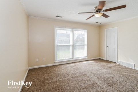 a living room with carpet and a ceiling fan
