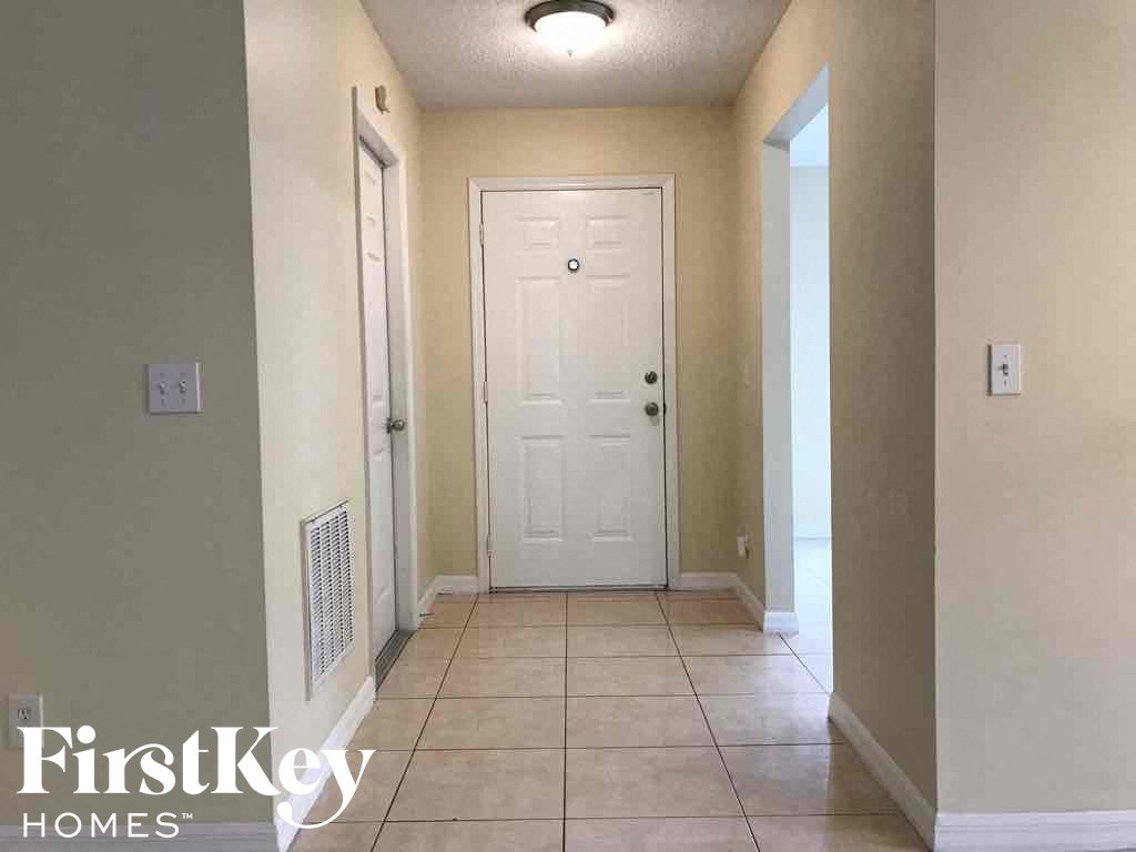 A hallway with a white door and a light switch on the wall.