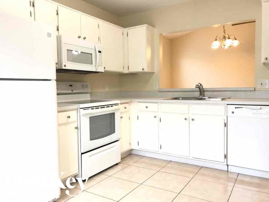 A kitchen with white appliances and cabinets.