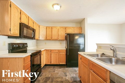 A kitchen with wooden cabinets and a black refrigerator.