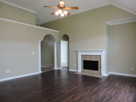 an empty living room with a fireplace and a ceiling fan