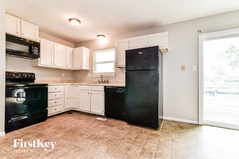 A kitchen with black appliances and white cabinets.