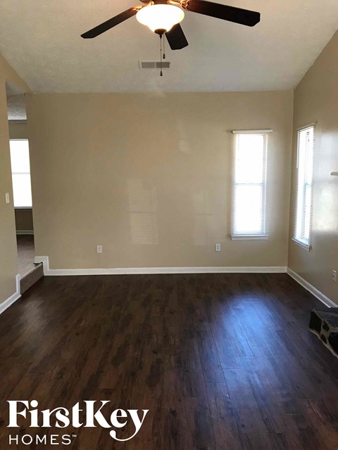 an empty living room with wood floors and a ceiling fan