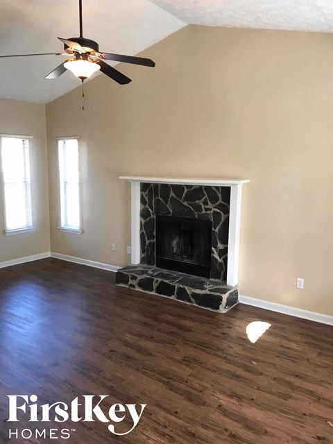 an empty living room with a fireplace and a ceiling fan