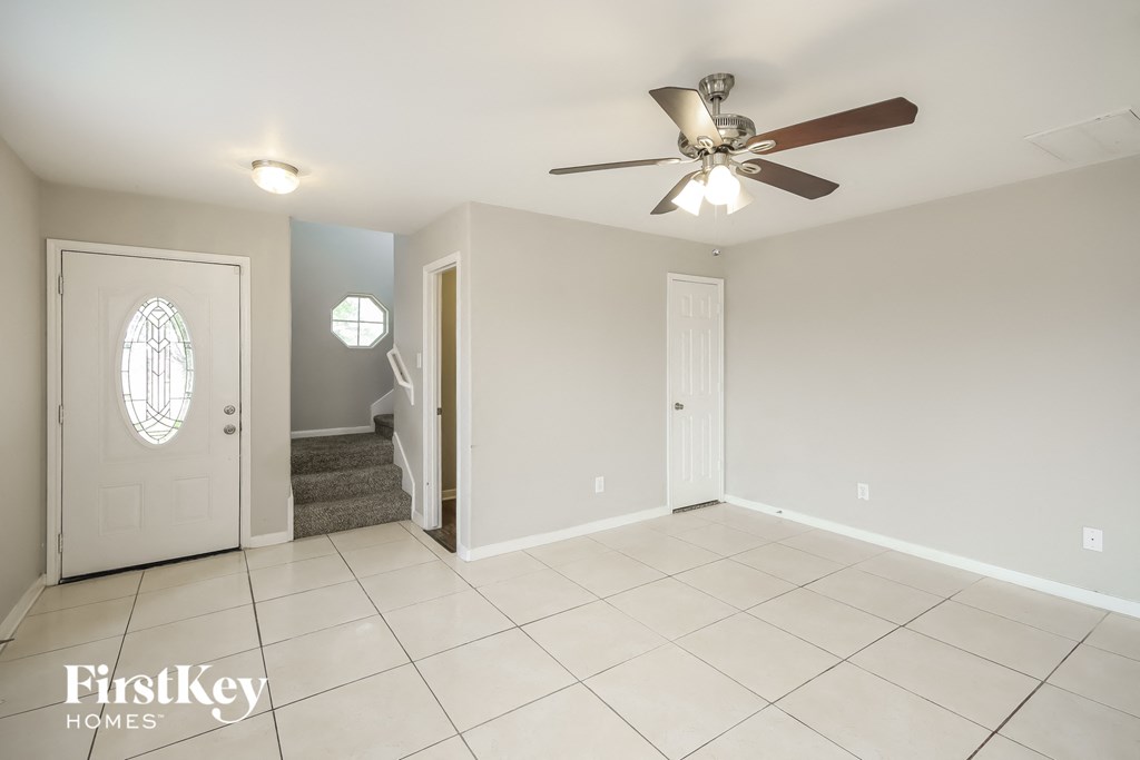 a clean and empty living room with a ceiling fan