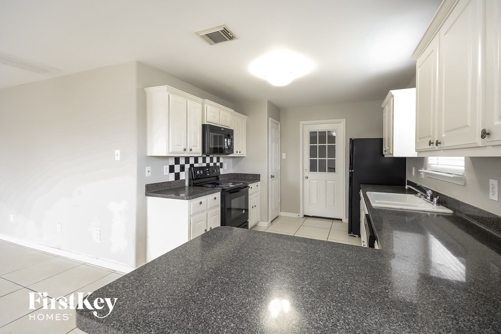 a kitchen with white cabinets and black counter tops