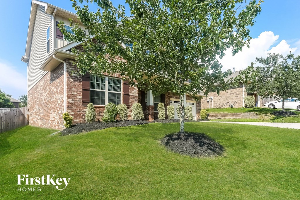 a tree in a yard in front of a house