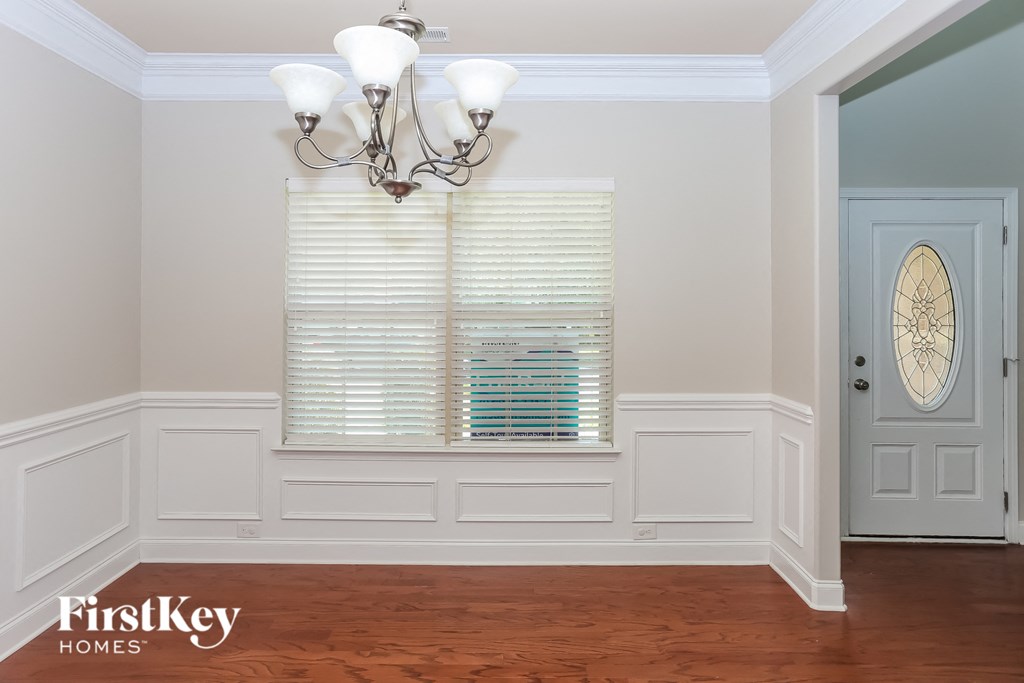a dining room with white wainscoting and a window