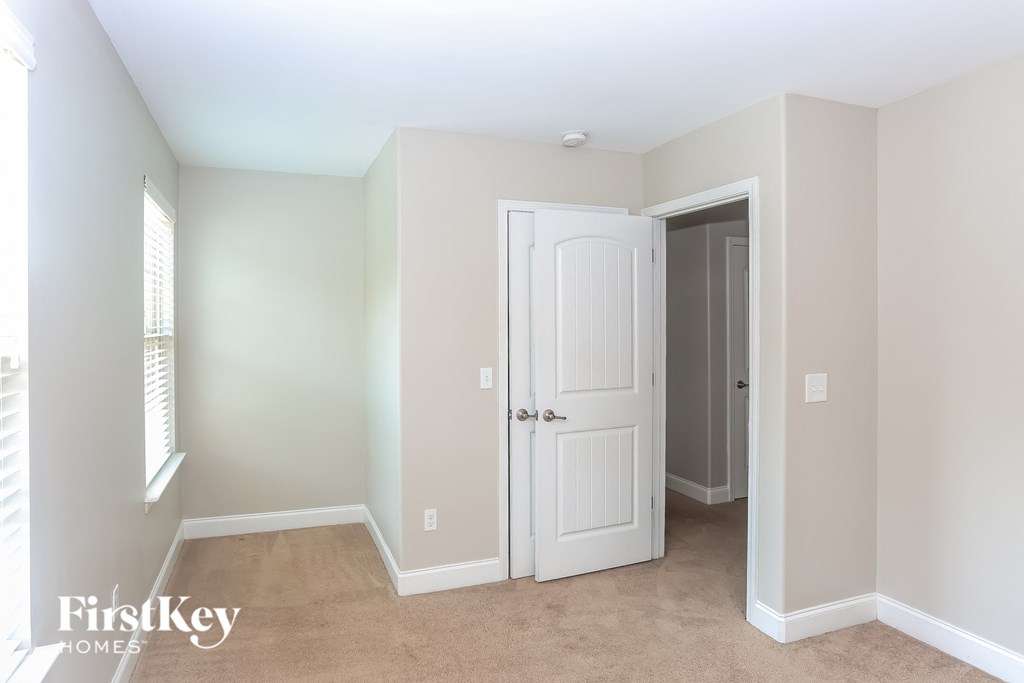 a bedroom with a white door and a hallway with a door to a closet