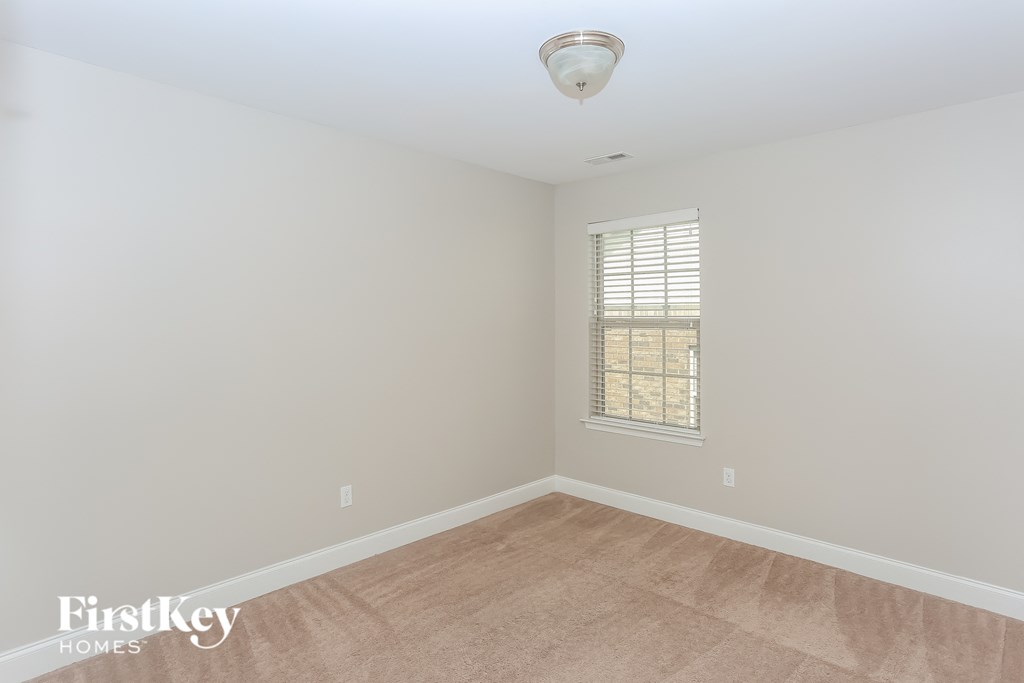 a bedroom with white walls and a window and a wooden floor