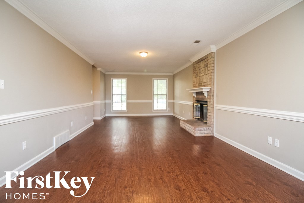 A spacious room with wooden floors and a brick fireplace.