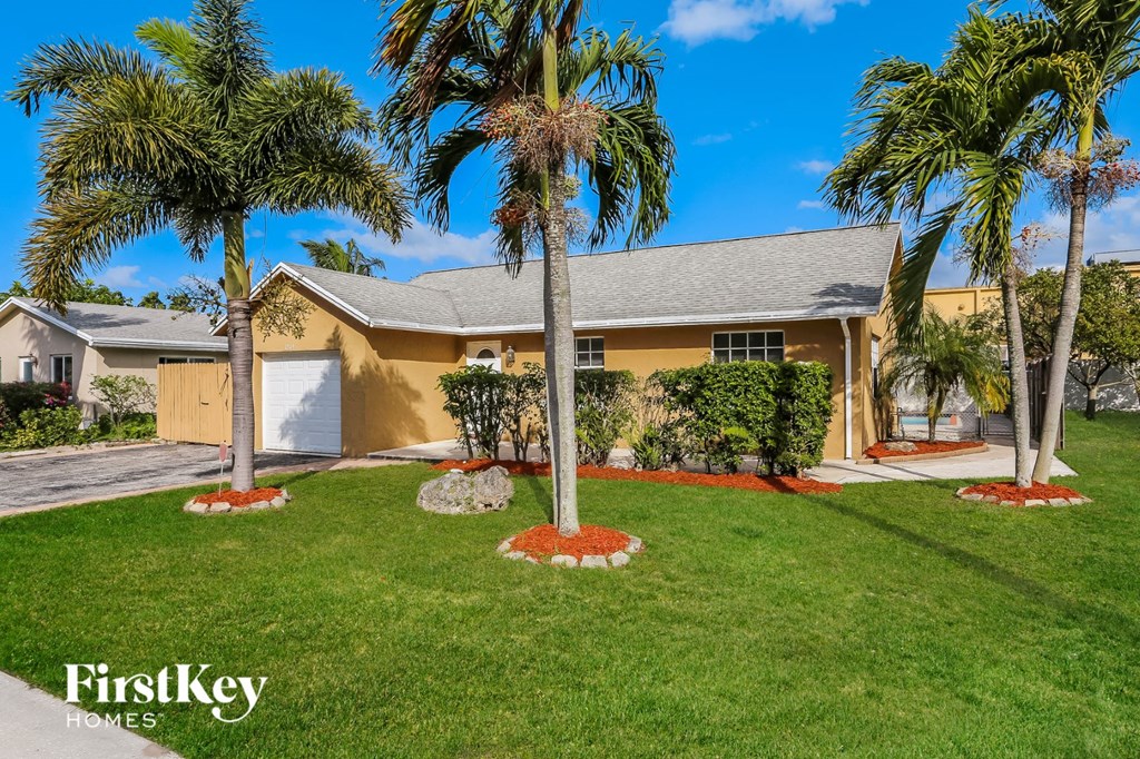 A house with a lawn and palm trees in front.
