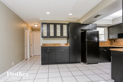 A kitchen with black cabinets and a marble countertop.