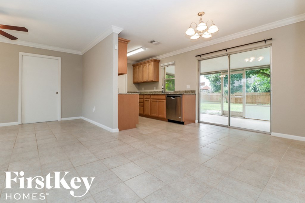 A spacious kitchen and living room with a sliding glass door leading to a backyard.