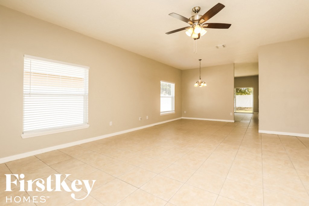 A spacious room with a ceiling fan and two windows.
