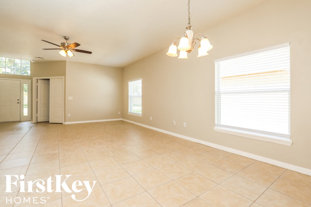 A spacious room with a ceiling fan and lighting fixture.