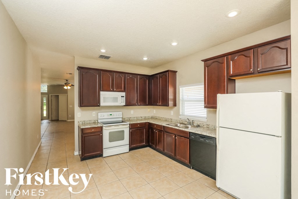 A kitchen with brown cabinets and white appliances.