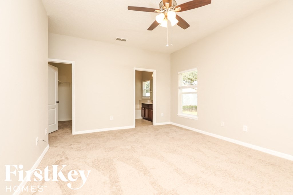 A spacious room with a ceiling fan and light fixture.