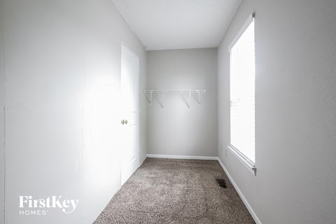 A white bedroom with a carpet floor and a window.