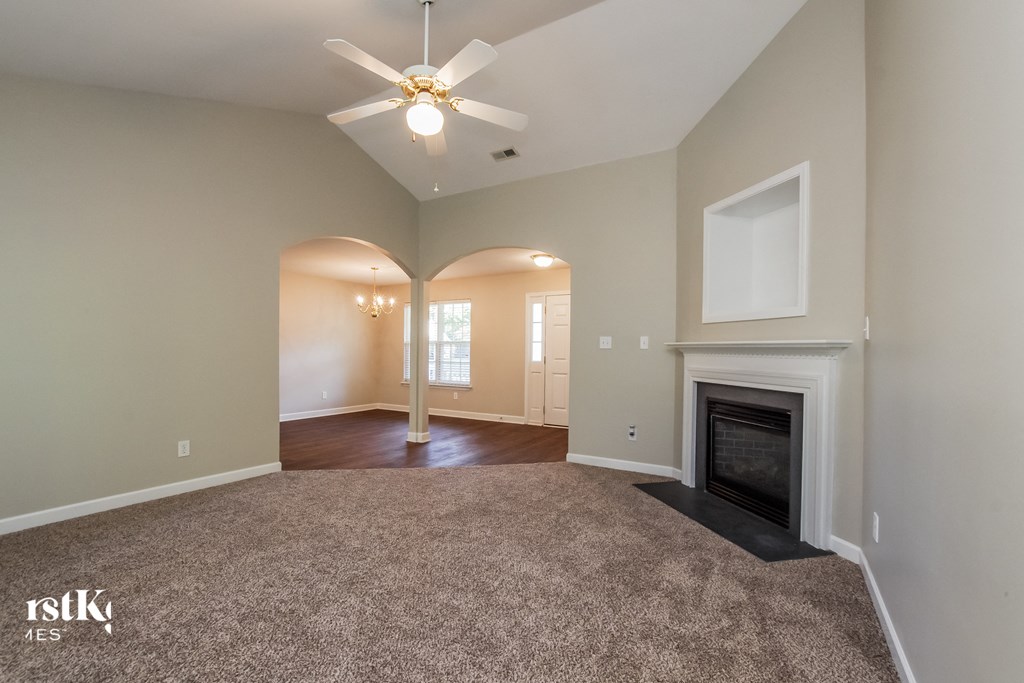 A spacious room with a fireplace and a ceiling fan.
