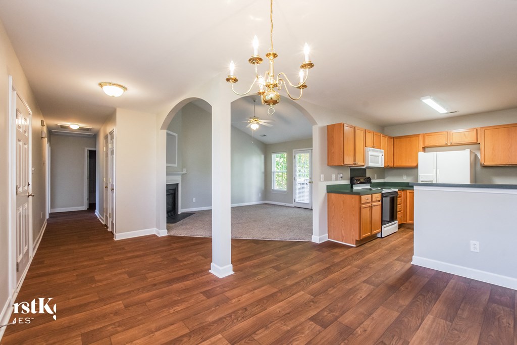 A spacious living room with hardwood floors and a chandelier.