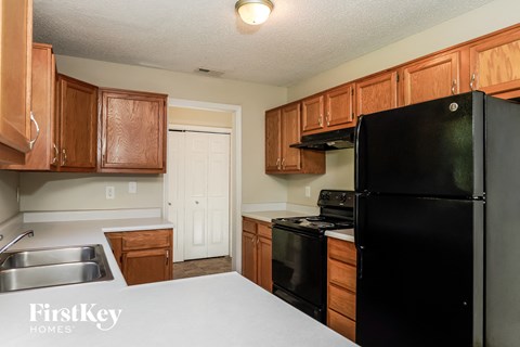 A kitchen with wooden cabinets and a black refrigerator.