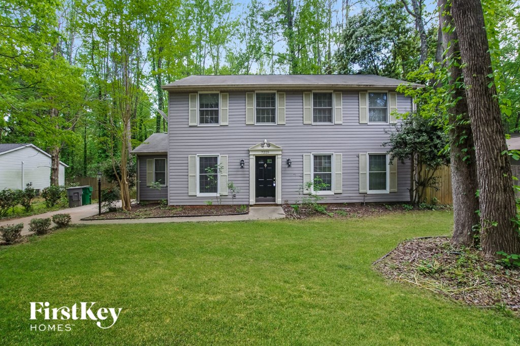 a gray house with a green lawn and trees