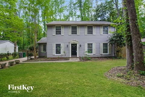 a gray house with a green lawn and trees