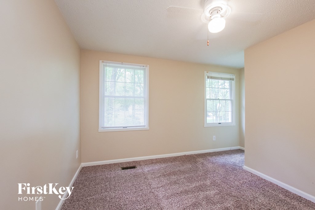 an empty room with carpet and two windows