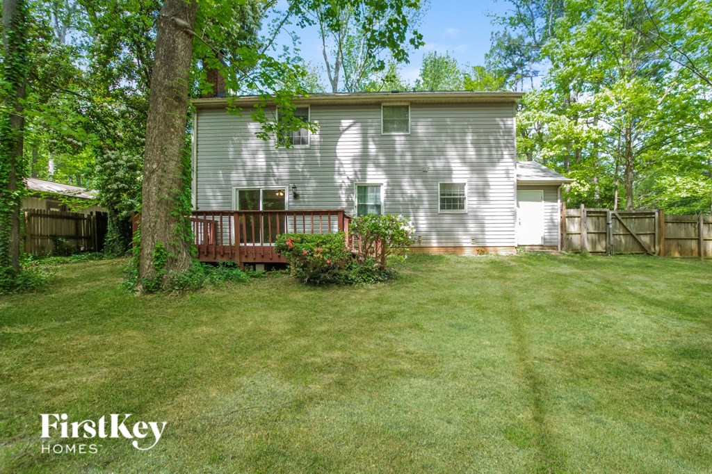 a backyard with a white house and a wooden deck