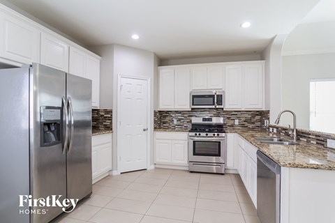 a large kitchen with white cabinets and stainless steel appliances