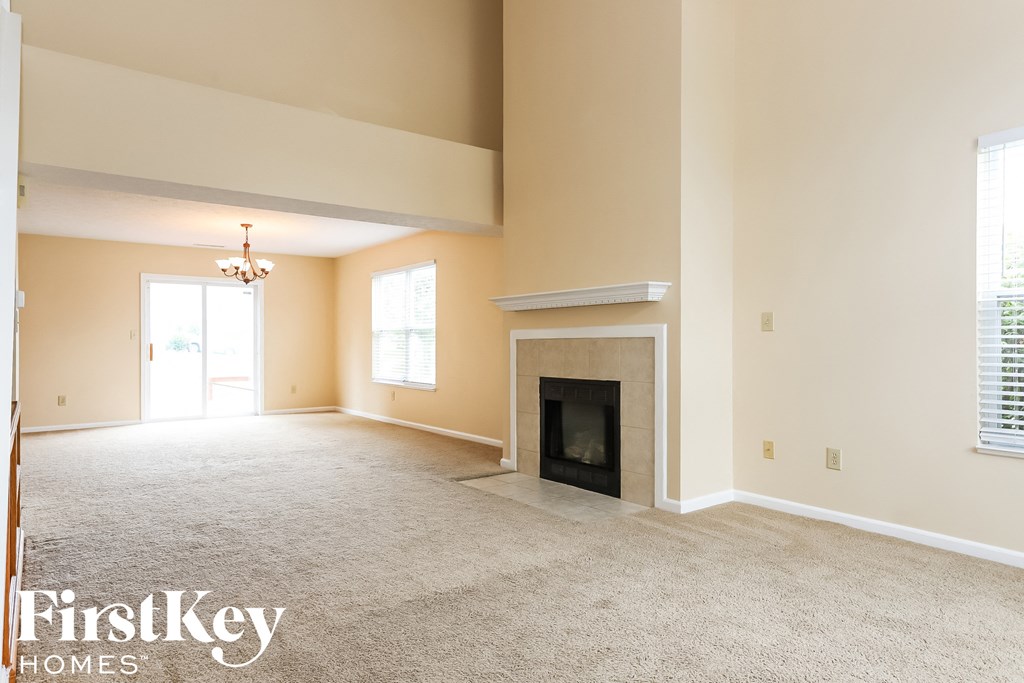 A spacious living room with a fireplace and a chandelier.