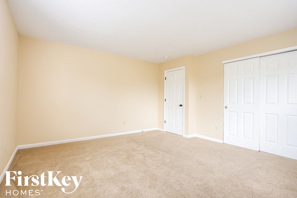 A room with a carpeted floor and two white doors.