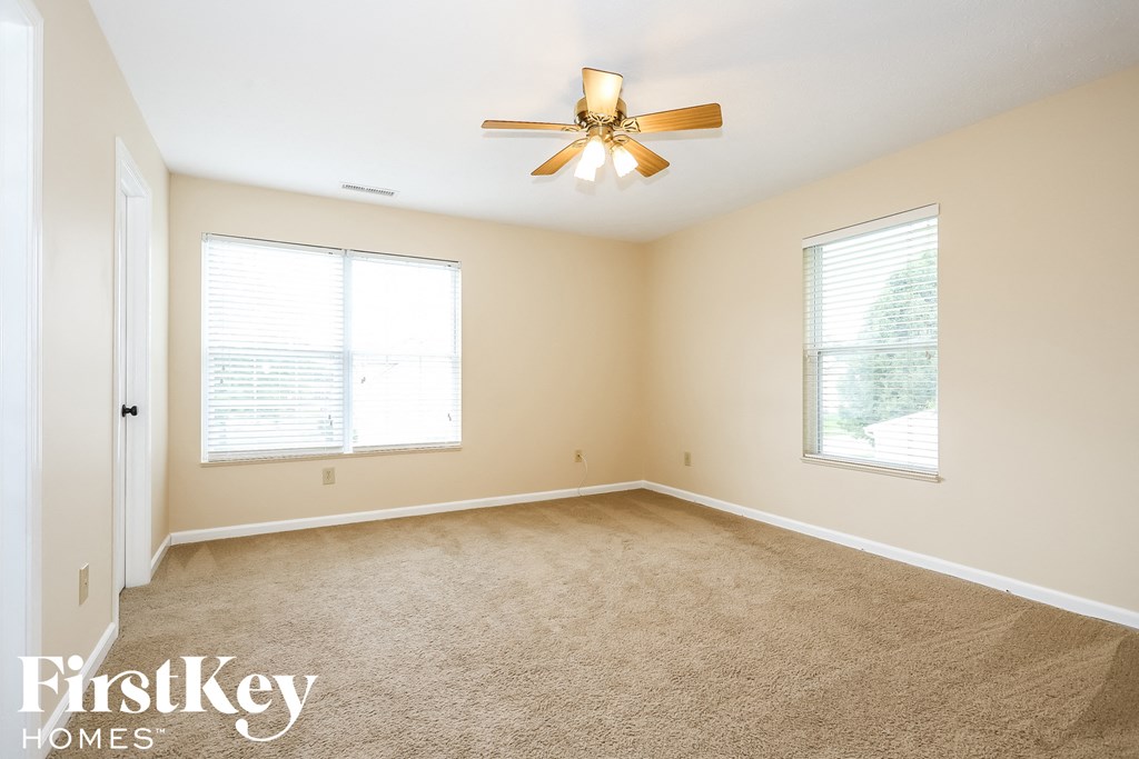 A room with a carpet floor and a ceiling fan.