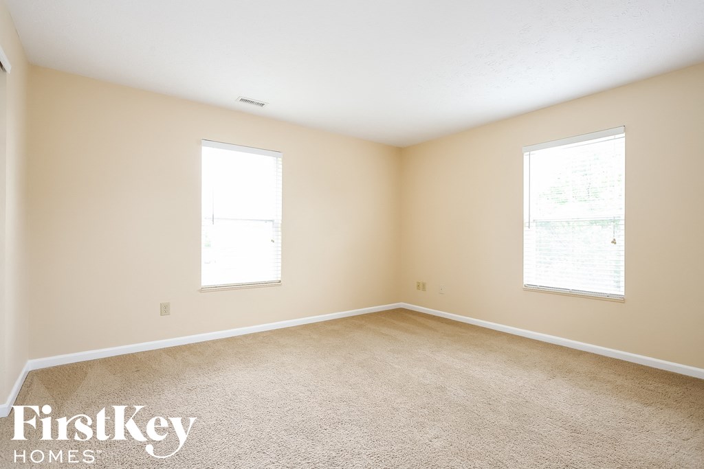 A room with two windows and a carpeted floor.